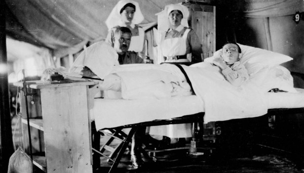 Original title:  Wounded World War Canadian soldier in No. 2 Hospital, with visitor and attending nurses. 